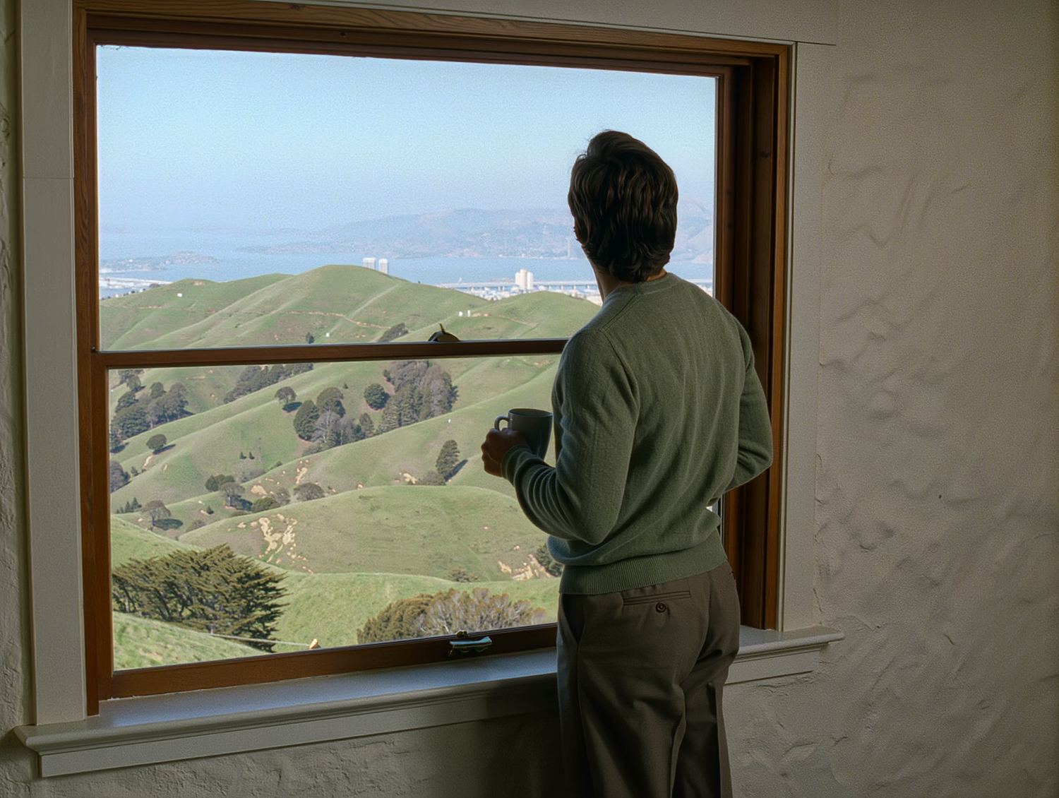 A professional with a coffee takes a quiet moment at a window before a meeting